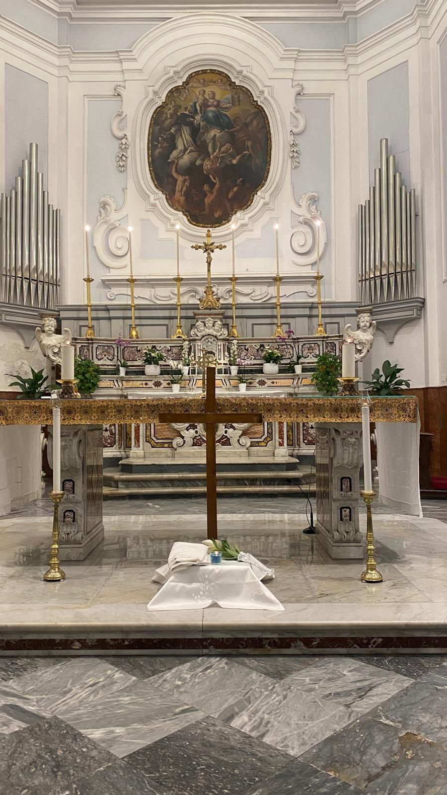 Il presbiterio della chiesa: l'altare in marmi colorati, sei candelieri dorati, il dipinto ovale tra gli stucchi e le canne dell'organo.
